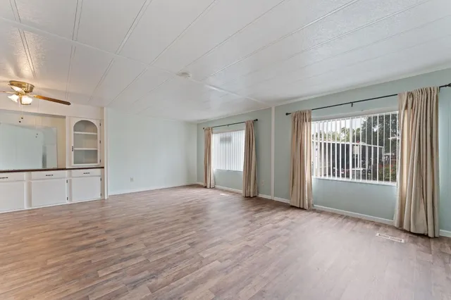 a view of an empty room with window and wooden floor