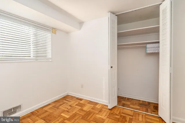 a view of an empty room with closet and a window