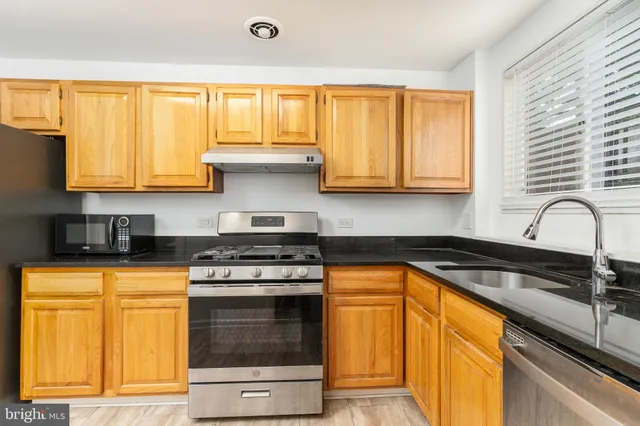 a kitchen with granite countertop wooden cabinets and a stove top oven