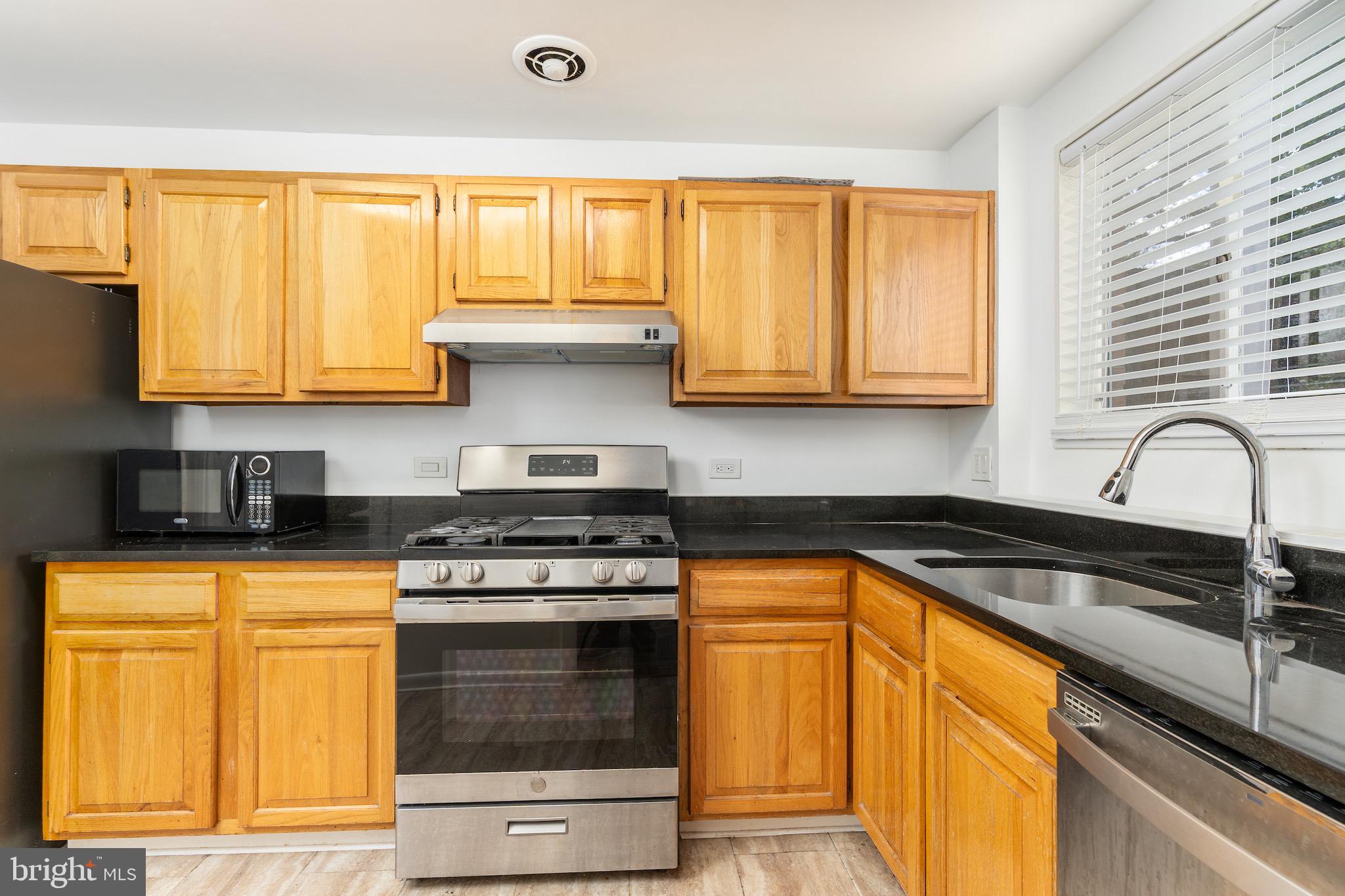 10423 Montrose Avenue, Unit 10423 Bethesda, MD 20814 - Photo 5 of 22 a kitchen with granite countertop wooden cabinets and a stove top oven