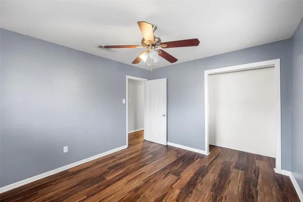 a view of a room with wooden floor and a ceiling fan