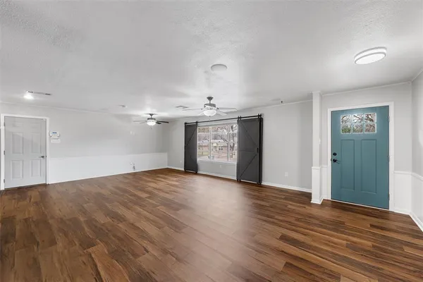 a view of an empty room with window and wooden floor