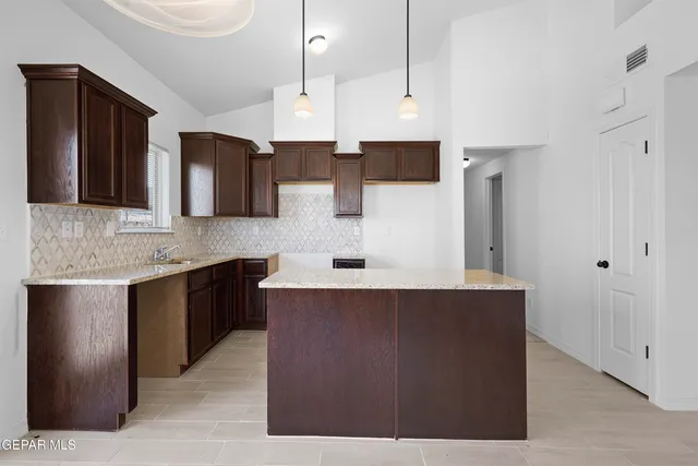 a kitchen with stainless steel appliances a sink a stove a refrigerator a center island and cabinets