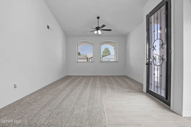 an empty room with windows and ceiling fan