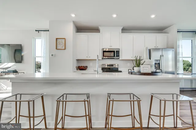 a living room with furniture kitchen view and a large window