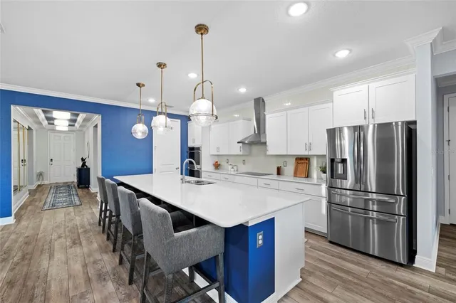 a large kitchen with stainless steel appliances kitchen island granite countertop a refrigerator a sink dishwasher and a dining table with wooden floor