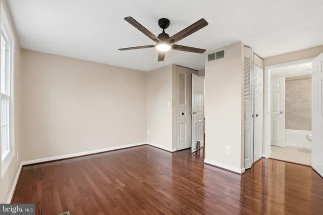 an empty room with wooden floor and a ceiling fan