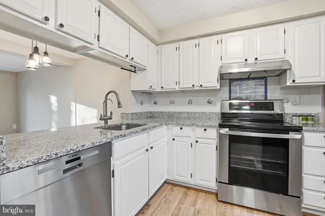 a kitchen with granite countertop a stove sink and cabinets