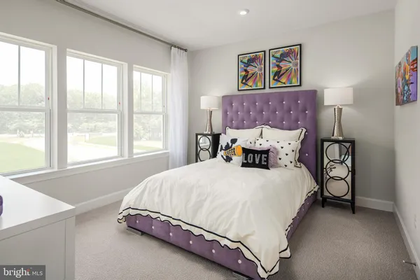 a bed sitting in a spacious bedroom next to a window