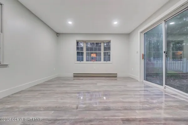 an empty room with wooden floor and windows