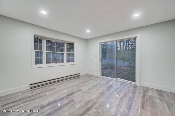 a view of empty room with wooden floor and window