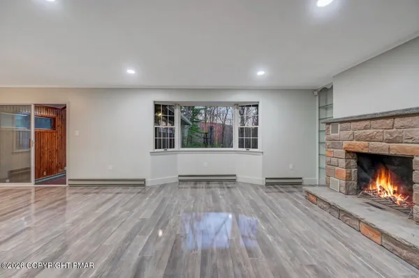 an empty room with wooden floor fireplace and windows