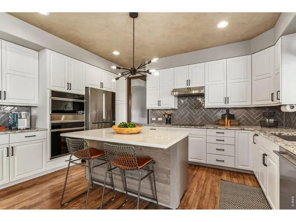 a kitchen with stainless steel appliances a stove a sink and white cabinets