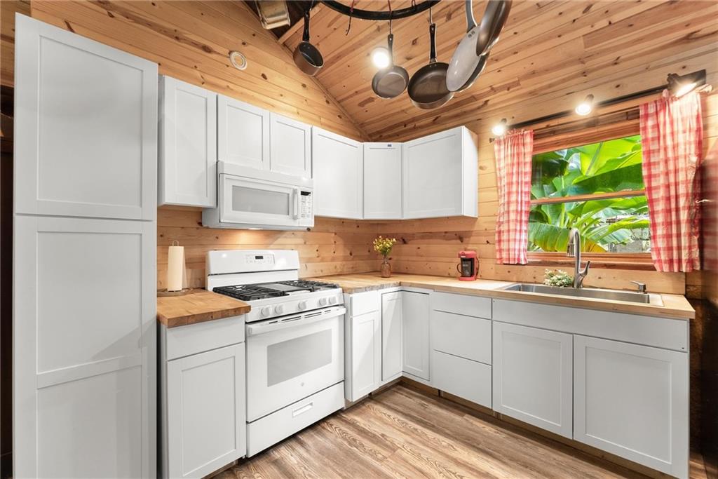 59 Rocket Drive Cleveland, GA 30528 - Photo 12 of 25 a kitchen with stainless steel appliances granite countertop a sink a stove and white cabinets with wooden floor