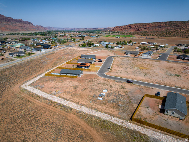 212 Lidia Circle, Unit 17 Moab, UT 84532 - Photo 5 of 24 New construction homes featuring modern architectural styles, individual fencing, and paved roads, set against a backdrop of natural rock formations and distant greenery