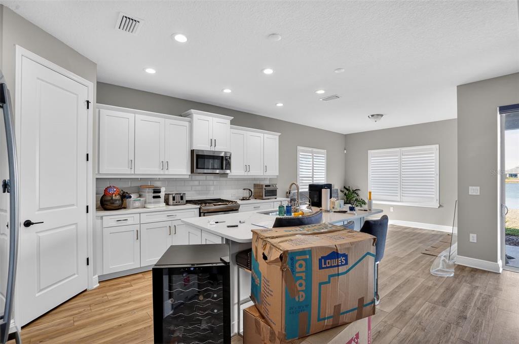 10710 Falling Leaf Court Parrish, FL 34219 - Photo 12 of 50 a kitchen with stainless steel appliances kitchen island granite countertop a stove a sink a refrigerator and white cabinets