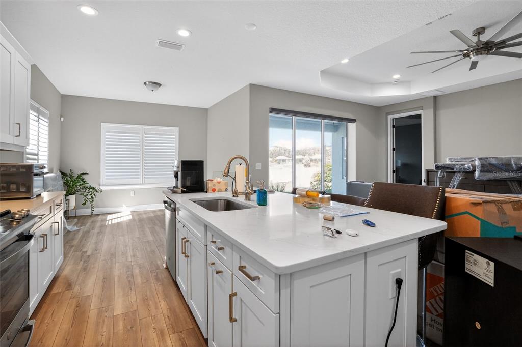 10710 Falling Leaf Court Parrish, FL 34219 - Photo 14 of 50 a kitchen with sink stove and white cabinets with wooden floor