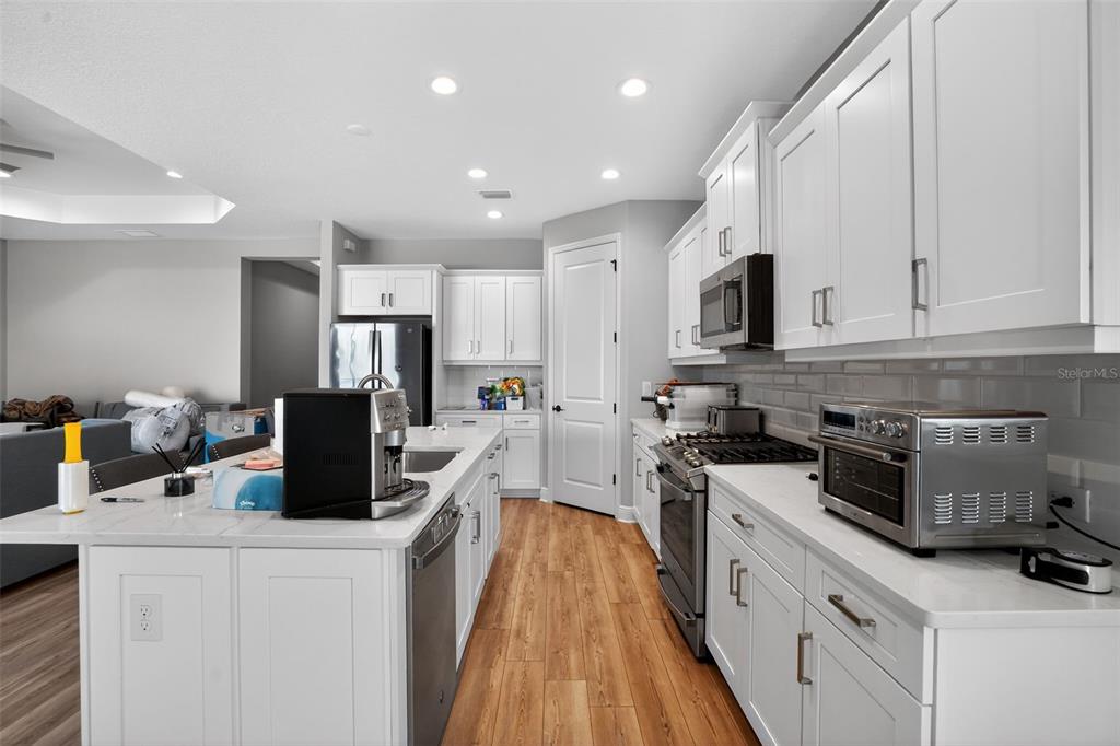 10710 Falling Leaf Court Parrish, FL 34219 - Photo 15 of 50 a kitchen with stainless steel appliances a stove top oven a sink a refrigerator white cabinets and a refrigerator
