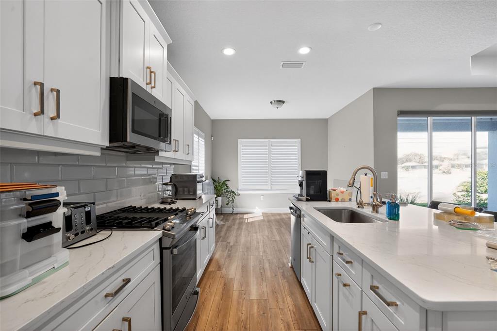 10710 Falling Leaf Court Parrish, FL 34219 - Photo 18 of 50 a kitchen with stainless steel appliances a sink stove top oven and cabinets