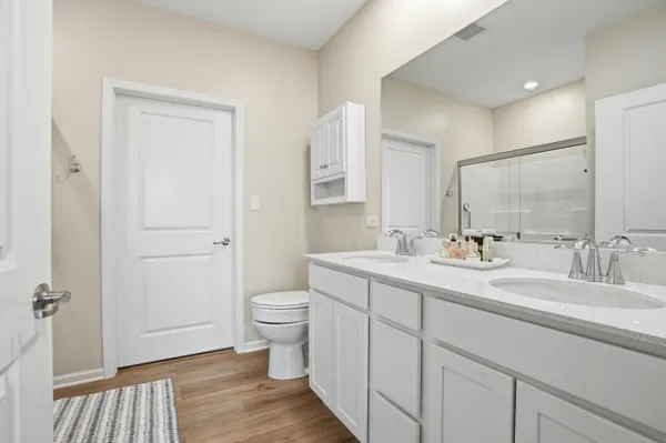 a spacious bathroom with a toilet sink double vanity and mirror