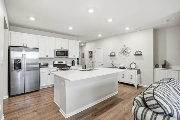 a large white kitchen with wooden floor and stainless steel appliances