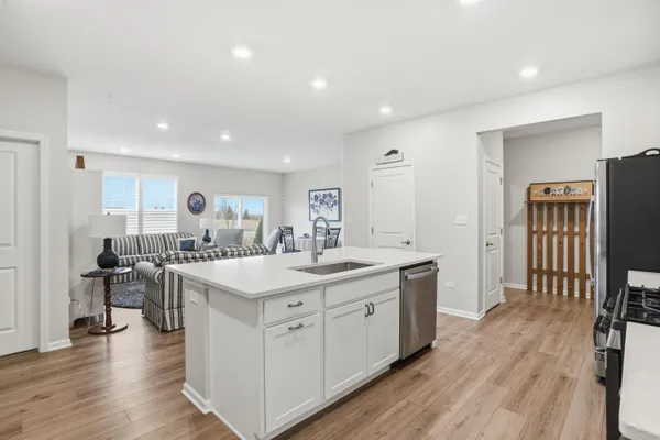 a large kitchen with kitchen island a sink dishwasher a dining table and chairs with wooden floor