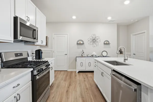 a kitchen with stainless steel appliances a sink dishwasher stove microwave and refrigerator with wooden floor