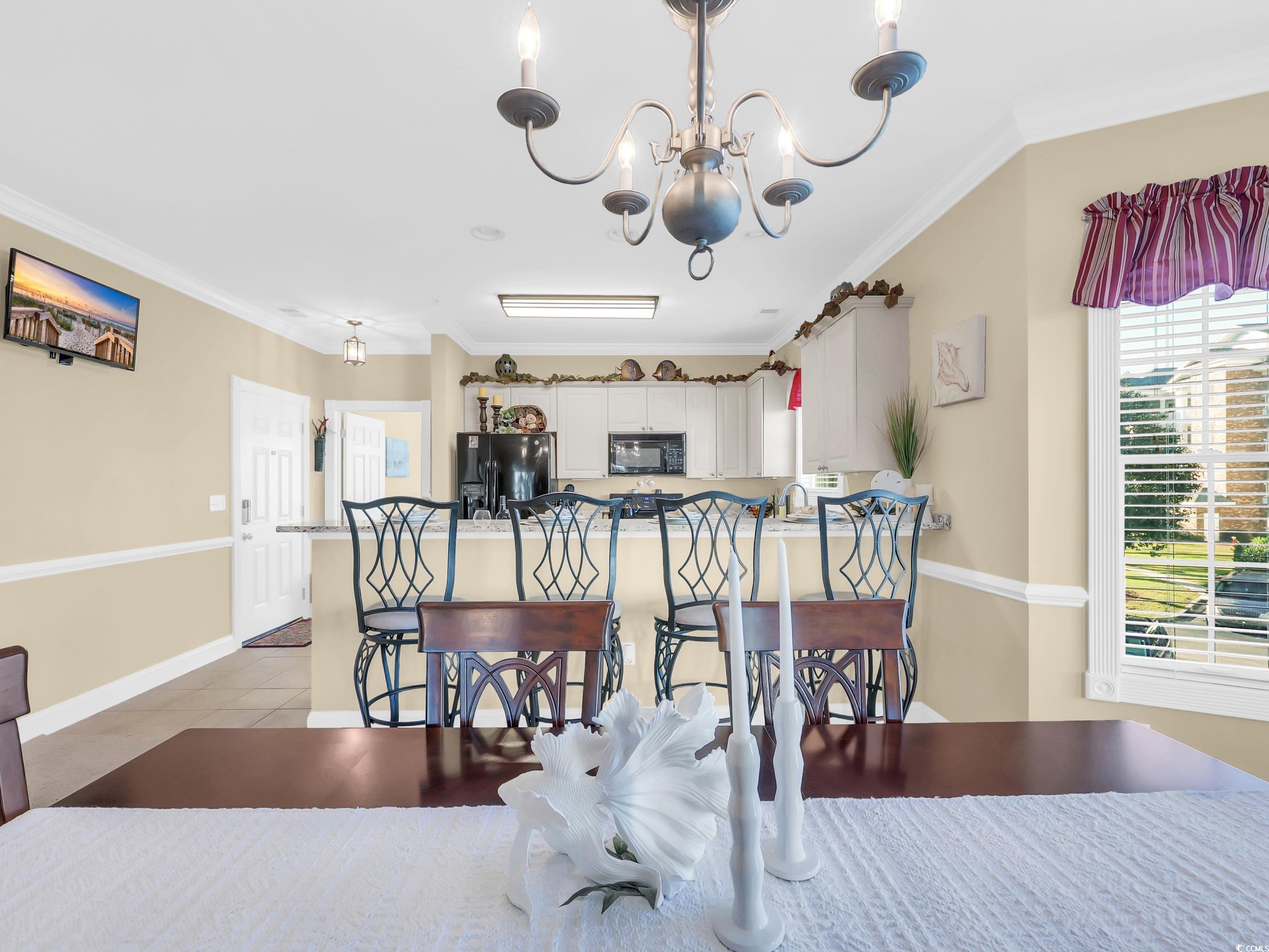 4833 Luster Leaf Circle, Unit 201 Myrtle Beach, SC 29577 - Photo 12 of 39 Dining room featuring crown molding, a chandelier, and light tile patterned floors