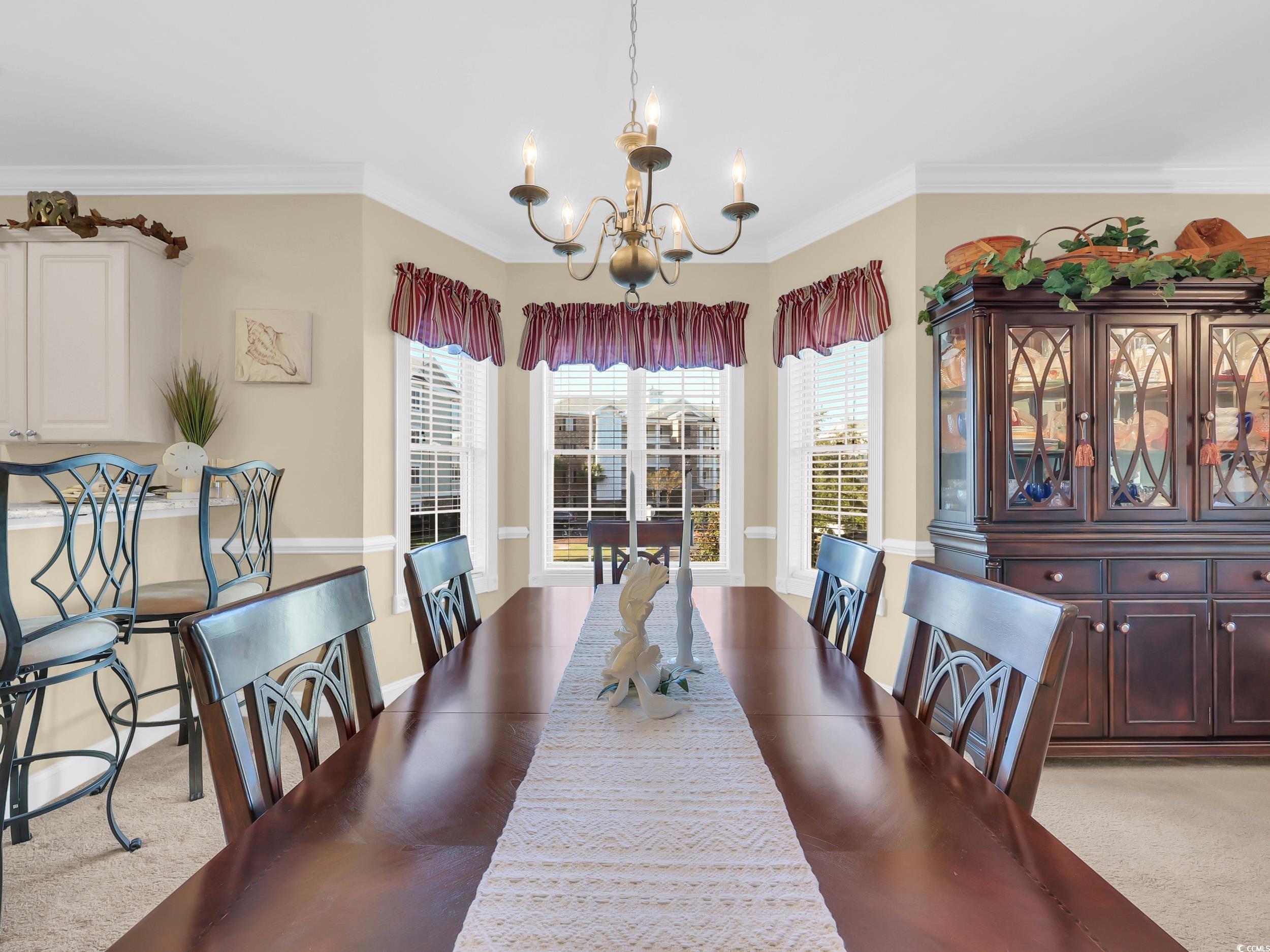 4833 Luster Leaf Circle, Unit 201 Myrtle Beach, SC 29577 - Photo 13 of 39 Dining area with light colored carpet, crown molding, and a chandelier