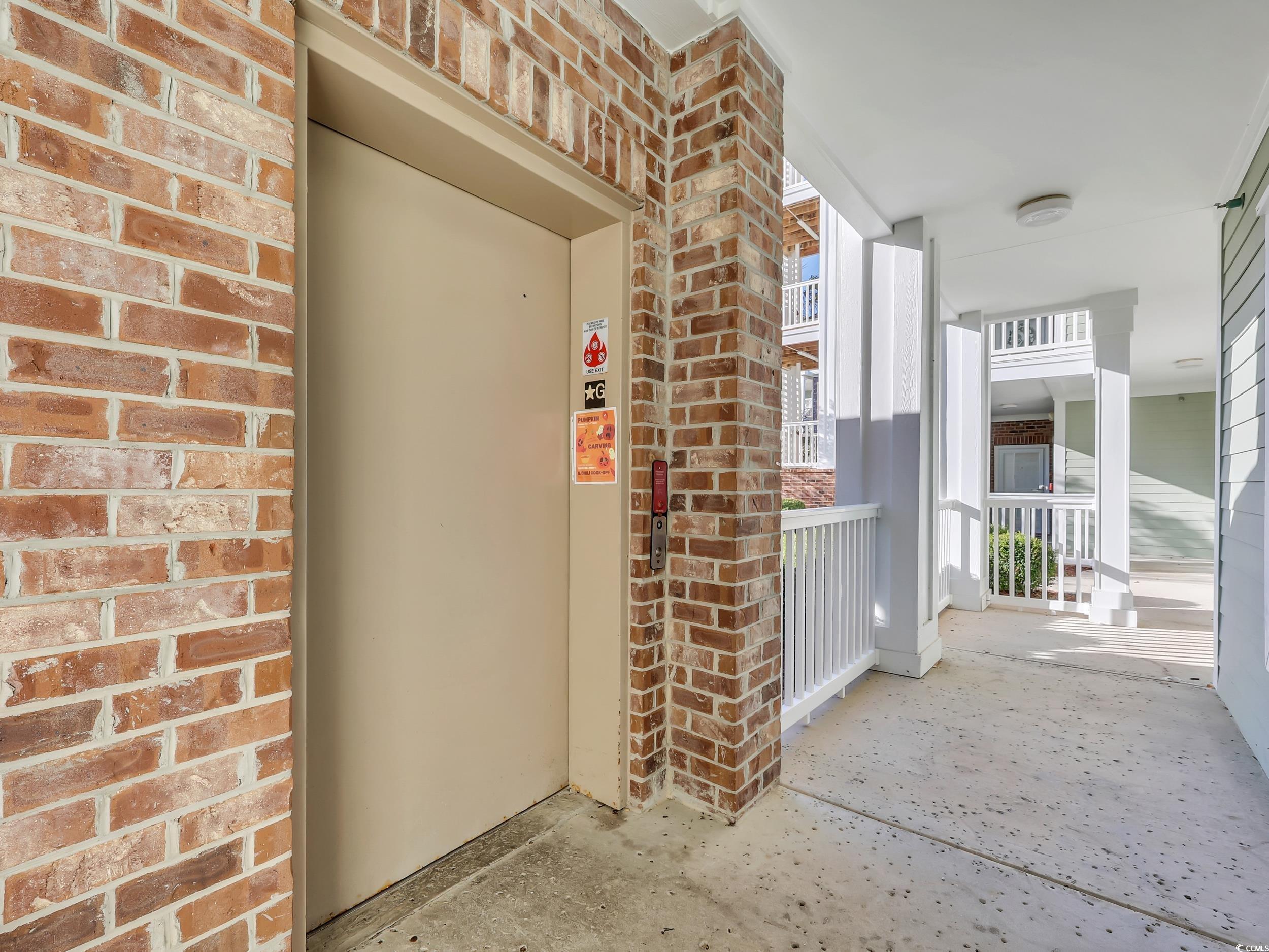 4833 Luster Leaf Circle, Unit 201 Myrtle Beach, SC 29577 - Photo 4 of 39 Property entrance featuring elevator, brick siding, and covered porch
