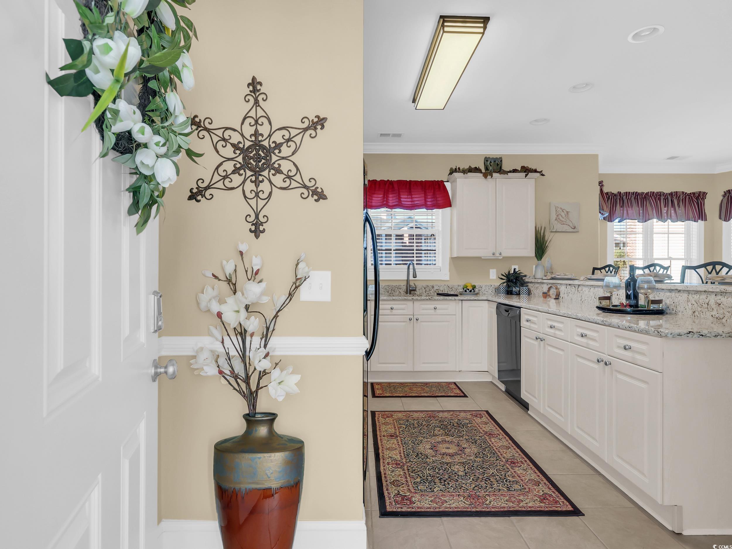 4833 Luster Leaf Circle, Unit 201 Myrtle Beach, SC 29577 - Photo 6 of 39 Kitchen featuring white cabinetry, light tile patterned floors, crown molding, light stone counters, and a peninsula