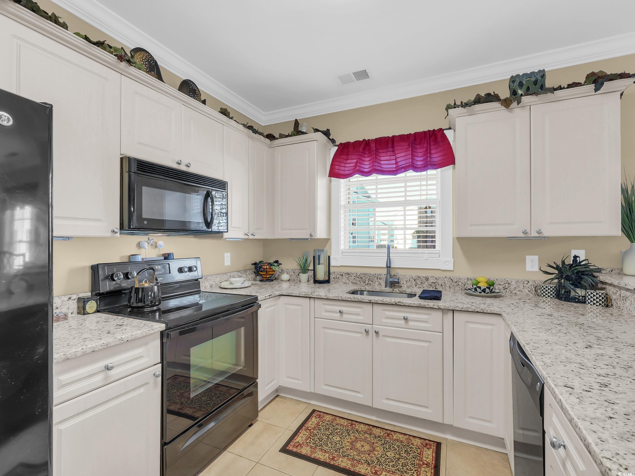4833 Luster Leaf Circle, Unit 201 Myrtle Beach, SC 29577 - Photo 8 of 39 Kitchen featuring black appliances, crown molding, white cabinetry, light stone counters, and light tile patterned floors