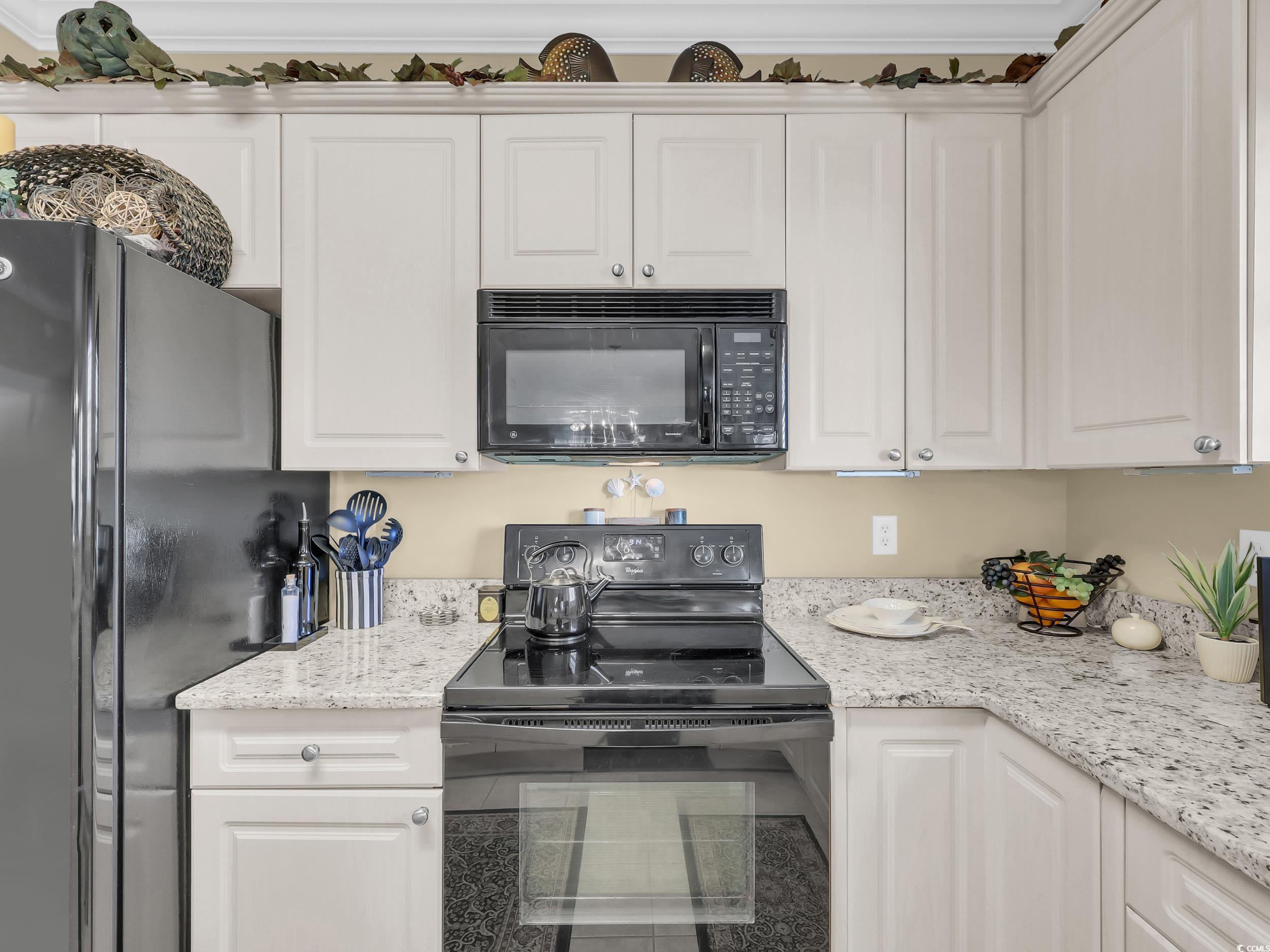4833 Luster Leaf Circle, Unit 201 Myrtle Beach, SC 29577 - Photo 9 of 39 Kitchen featuring black appliances, white cabinetry, and light stone countertops
