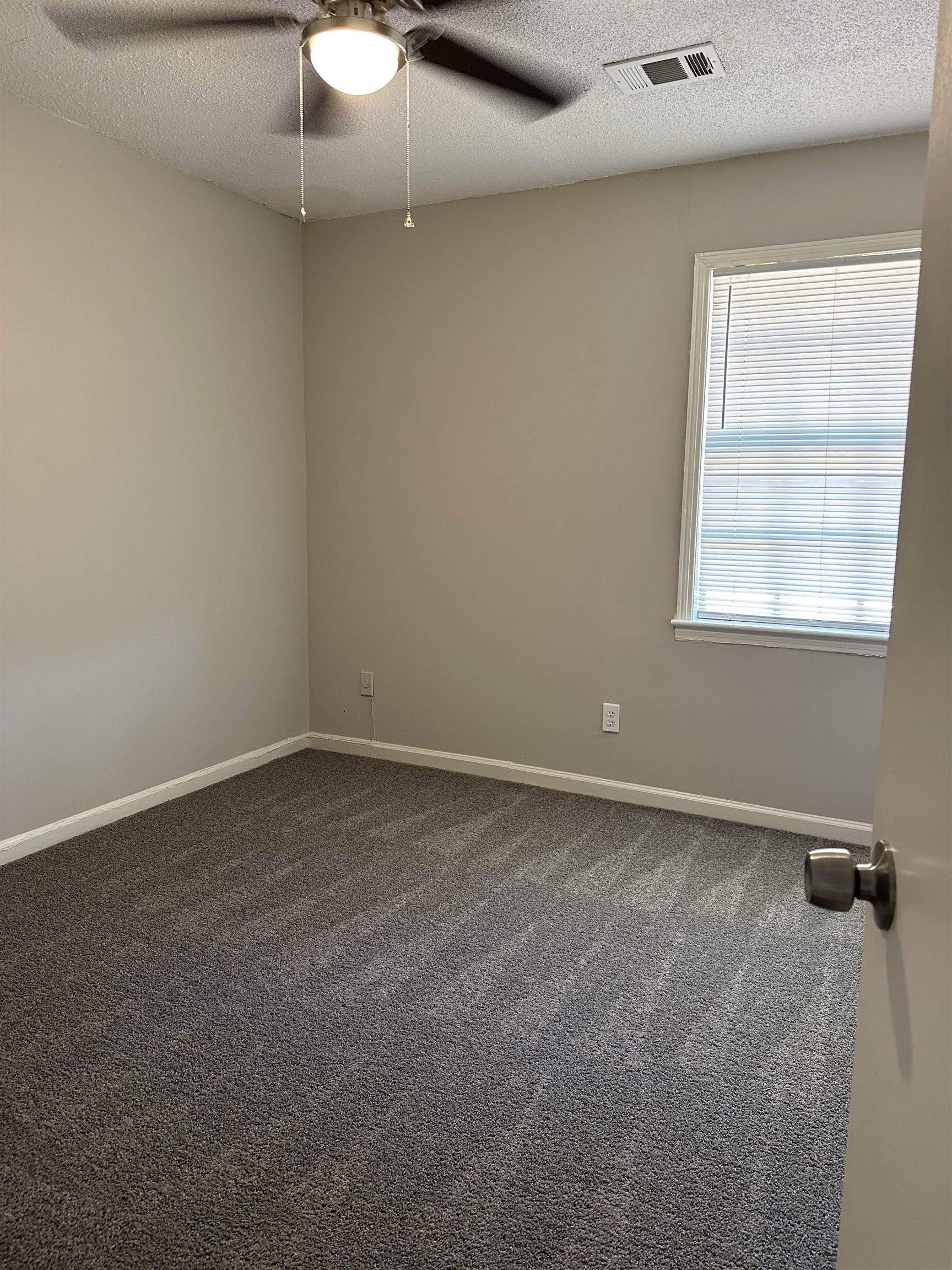 899 West Raines Road Memphis, TN 38109 - Photo 11 of 14 Neutral tone wall paint, textured ceiling, window with blinds, ceiling fan with integrated lighting, and carpet flooring