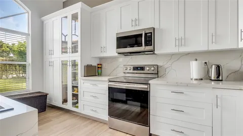 a kitchen with stainless steel appliances granite countertop white cabinets and a stove top oven