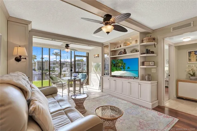 a living room with furniture a ceiling fan and a large window