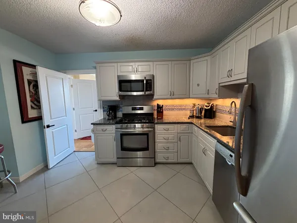 a kitchen with stainless steel appliances granite countertop a refrigerator stove and sink