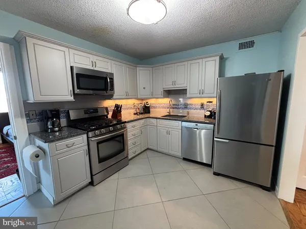 a kitchen with granite countertop a refrigerator stove top oven and sink