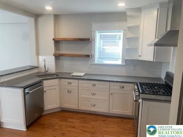 a kitchen with granite countertop a sink cabinets stainless steel appliances and a window
