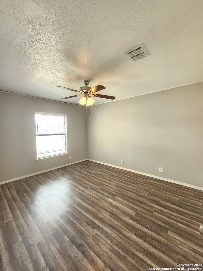 5303 Walnut Vista Drive San Antonio, TX 78247 - Photo 11 of 18 an empty room with wooden floor chandelier fan and windows