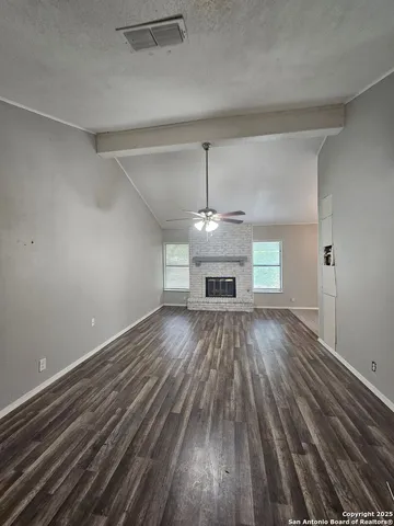 a view of empty room with a fireplace and wooden floor