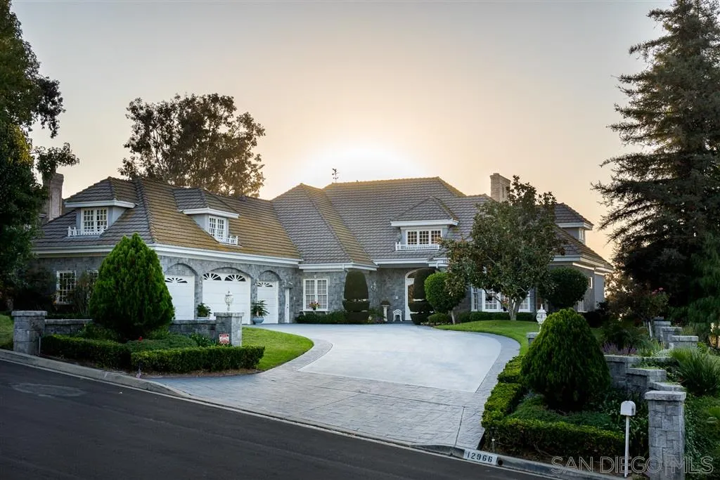 a view of a white house next to a yard with plants and trees