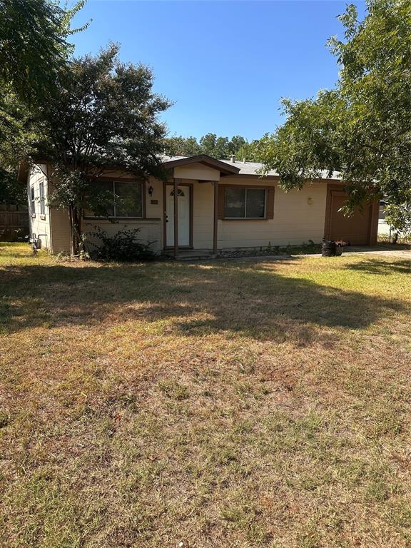 a view of a yard in front of a house with a large tree