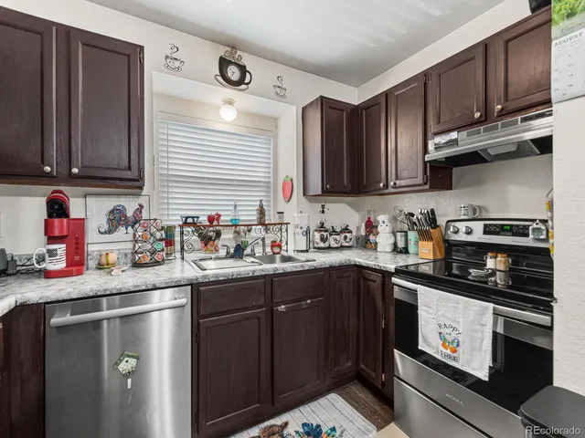 a kitchen with stainless steel appliances granite countertop a sink stove refrigerator and cabinets