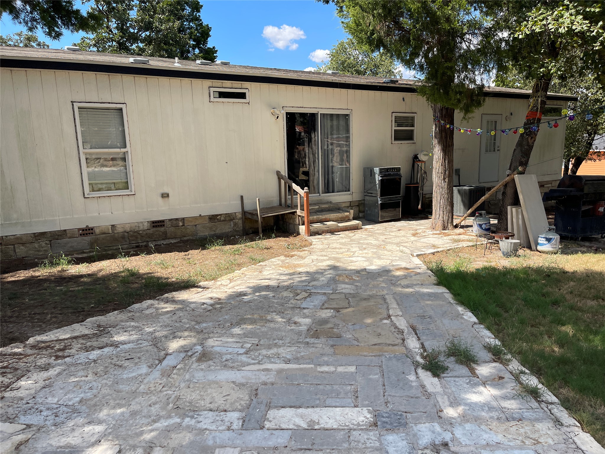 103 Azalea Avenue Elgin, TX 78621 - Photo 22 of 23 Stone pathways wind through the shaded backyard, leading directly to the rear entrance.