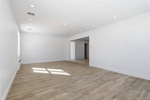 an empty room with wooden floor and natural light