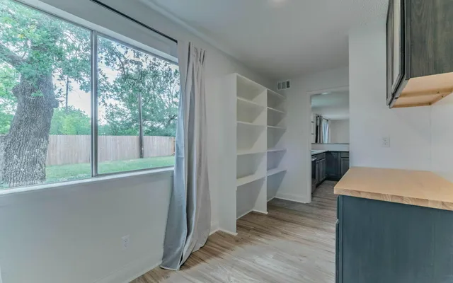 an empty room with wooden floor a ceiling fan and windows