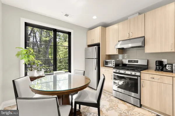 a kitchen with stainless steel appliances a stove a table and chairs