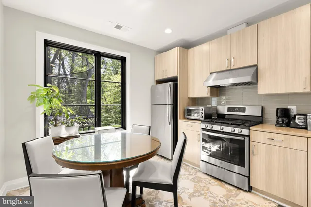 a kitchen with stainless steel appliances a stove a table and chairs