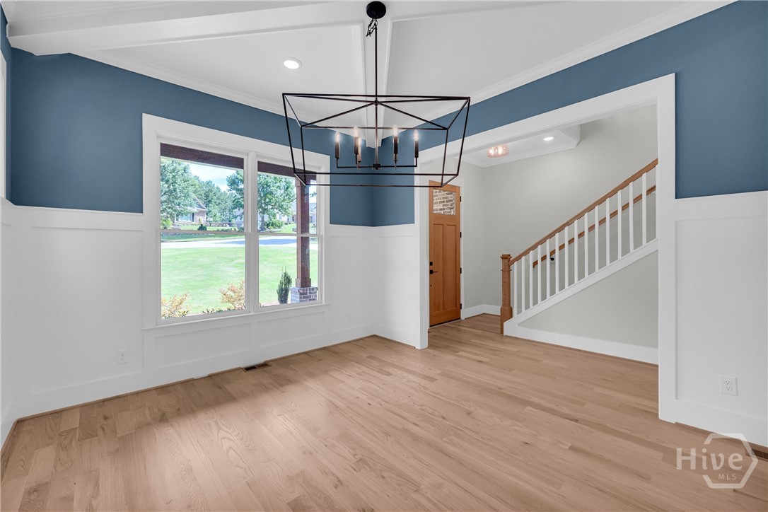 2476 St Martin Way Monroe, GA 30656 - Photo 6 of 75 Spacious interior featuring wood-finish flooring, wainscoting, and a modern geometric chandelier in the Dining Room